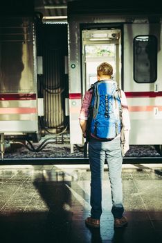 Young hipster tourist with backpack on the train station. Holiday tourist concept.