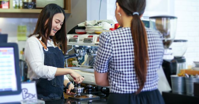 Barista serving customer and Woman is paying for coffee by credit card in coffee shop