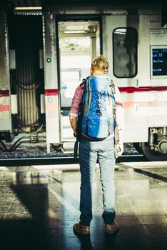 Young hipster tourist with backpack on the train station. Holiday tourist concept.