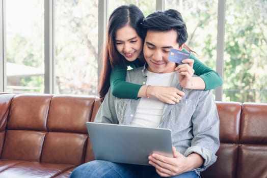 Couple Love Having Enjoy Relaxation on Sofa at Their Home, Attractive Asian Couple Happiness in Romantic Moments at Living Room While Online Shopping and Work at Home. Relaxing and Lifestyles Concept