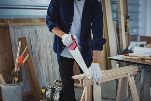 Asian man Carpenter working with technical drawing or blueprint construction paper lying on a workshop with carpentry tools and wood at home 