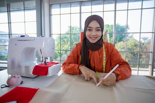 Small business of Muslim woman fashion designer Working and  using smart phone and tablet With Dresses at clothing store