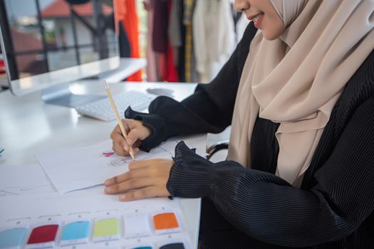 Small business of Muslim woman fashion designer Working and  using smart phone and tablet With Dresses at clothing store