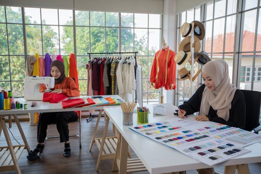 Small business of Muslim woman fashion designer Working and  using smart phone and tablet With Dresses at clothing store