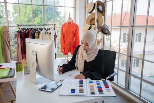 Small business of Muslim woman fashion designer Working and  using smart phone and tablet With Dresses at clothing store