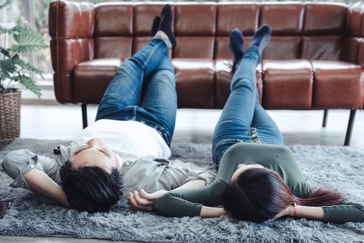 Young Couple Having Relaxing While Lying on Carpet at Their Home, Attractive Asian Couple Love are Relaxed Together at Home Living Room Flooring. Happy Moments and Couple Lifestyles Concept