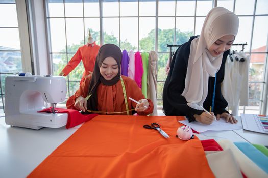 Small business of Muslim woman fashion designer Working and  using smart phone and tablet With Dresses at clothing store