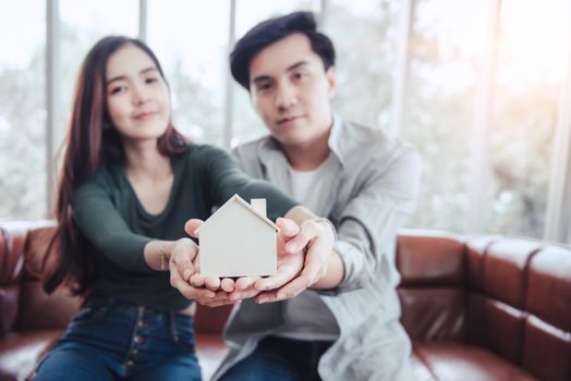 Couple Hands Holding Housing Model for Future Real Estate Saving, Attractive Asian Couple Hand Joint to Protection Home Property Togetherness. House Insurance and Residential Loan Investment Concept.