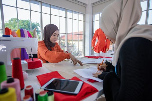 Small business of Muslim woman fashion designer Working and  using smart phone and tablet With Dresses at clothing store