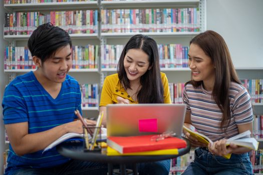 Group Asian  Students Smile and reading book and using notebook for helps to share ideas in the work and project. And also review the book before the exam