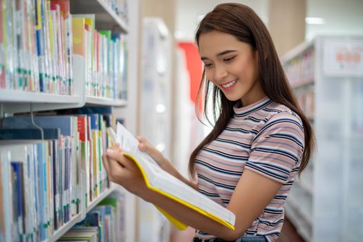 Asian female students smiling and reading Book  in library