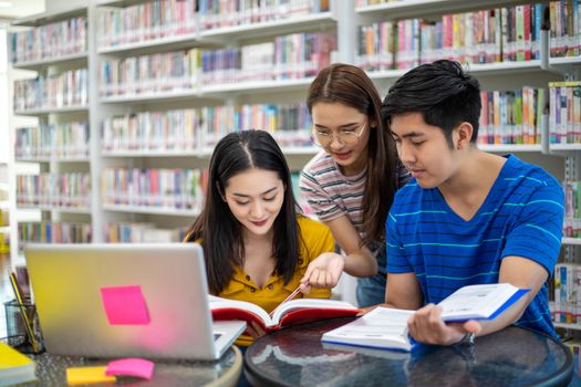 Group Asian  Students Smile and reading book and using notebook for helps to share ideas in the work and project. And also review the book before the exam