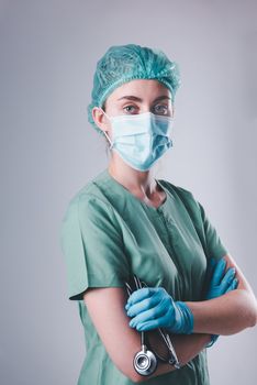 Female Doctor in Protective Mask and Medical Cap on Isolated Background, Closeup Portrait of Medicine Surgeon Doctor Wearing Medical Mask and Holding Stethoscope. Clinic Health Care/Doctors Occupation