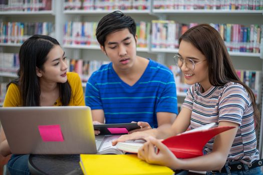 Group Asian  Students Smile and reading book and using notebook for helps to share ideas in the work and project. And also review the book before the exam