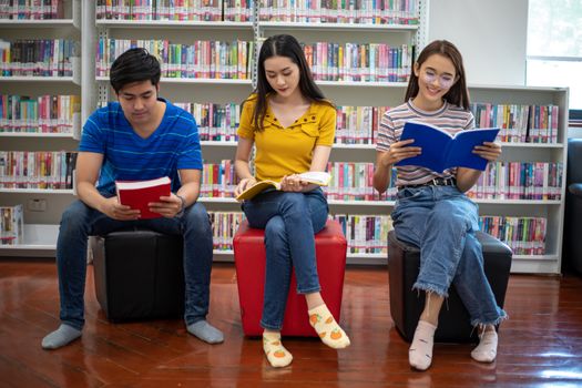 Group Asian  Students Smile and reading book and using notebook for helps to share ideas in the work and project. And also review the book before the exam