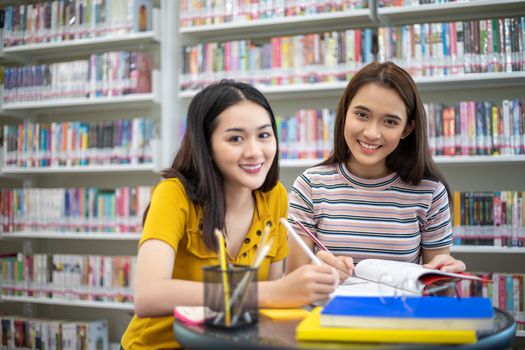 Group Asian  Students Smile and reading book and using notebook for helps to share ideas in the work and project. And also review the book before the exam