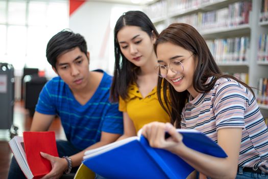 Group Asian  Students Smile and reading book and using notebook for helps to share ideas in the work and project. And also review the book before the exam