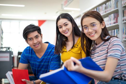 Group Asian  Students Smile and reading book and using notebook for helps to share ideas in the work and project. And also review the book before the exam