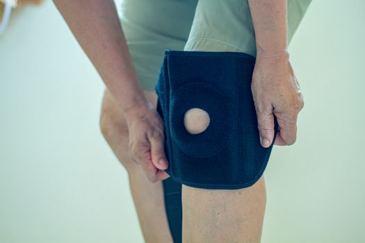 old Asian women to knee injury and use knee support brace on leg 