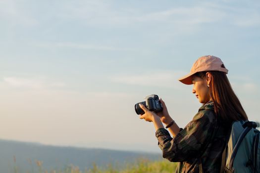 women asian with backpack taking a photo on view at sunrise seaside mountain peak