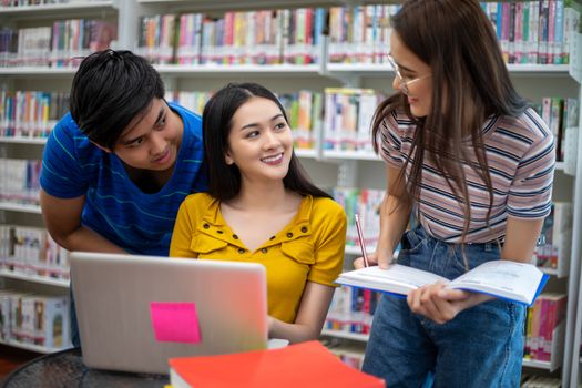 Group Asian  Students Smile and reading book and using notebook for helps to share ideas in the work and project. And also review the book before the exam