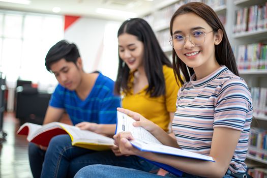 Group Asian  Students Smile and reading book and using notebook for helps to share ideas in the work and project. And also review the book before the exam