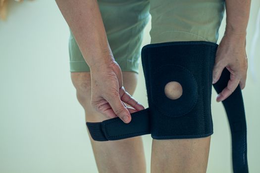 old Asian women to knee injury and use knee support brace on leg 