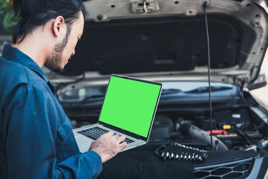 Mechanic Engineer is Diagnosing Car Engine and Electric Adjusting Transmission With Computer Laptop, Automobile Service Man Diagnostic Vehicle Car Engines Systems in Garage Workshop. Engineering Work