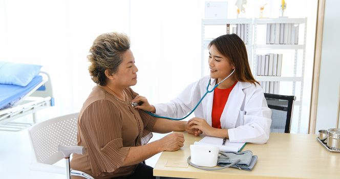 Doctor using stethoscope for examining old women patient in his at Hospitals