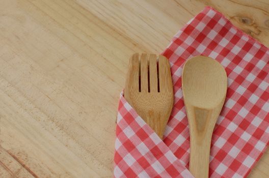 Wooden kitchen utensils and fabric on wooden background