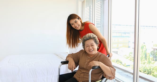 Cheerful woman taking care of her grandmother in wheelchair