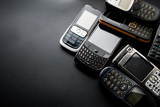 Old and obsoleted cellphones on a black background.