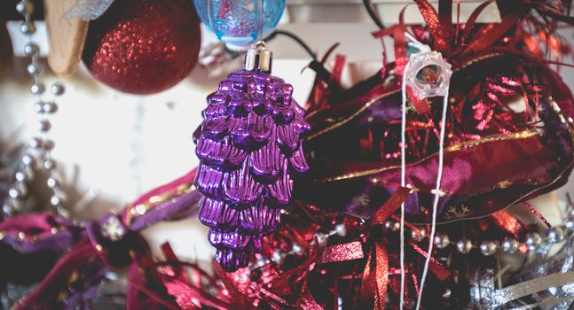 Christmas decoration made by children garlands, balls and pine cone on a fir tree made from wooden board at home