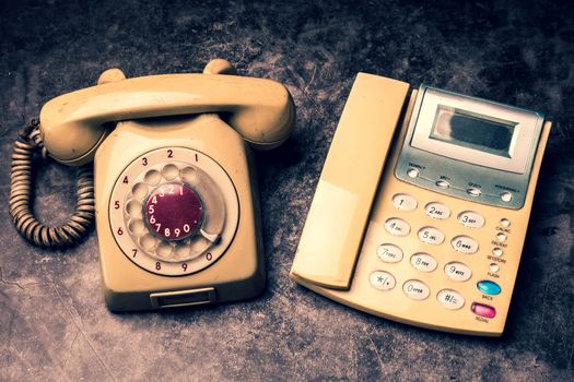 An old telephone with rotary dial and a landline on a grunge background.