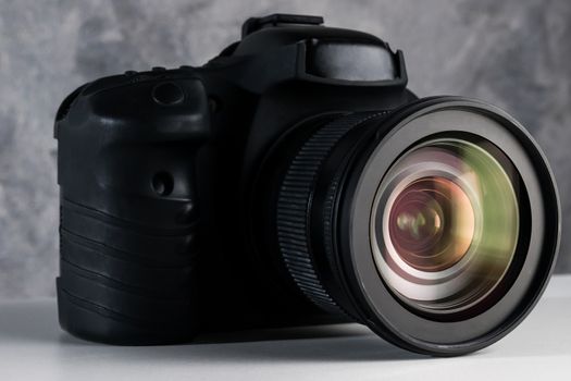 Black digital camera on a table with grunge background.