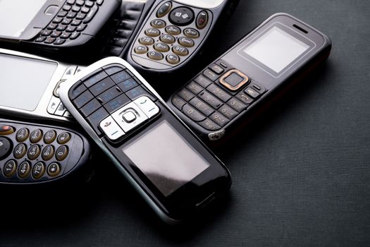 Old and obsoleted cellphones on a black background.