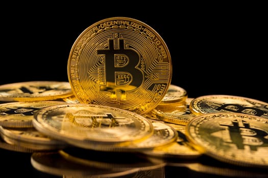 Golden coins with bitcoin symbol on a black background.