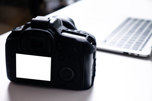 Blank screen digital camera and a computer laptop on a table.