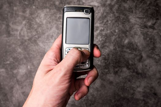 Close up of male hand press on button of an obsolete cellphone.