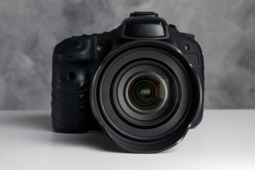 Black digital camera on a table with grunge background.