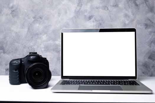 A black digital camera and a computer laptop on a table