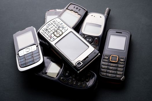 Old and obsoleted cellphones on a black background.