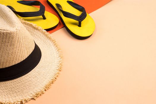 Beach hat and rubber slippers on colors background.