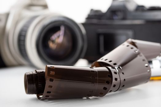 Single lens reflex cameras and a film roll on a white background.