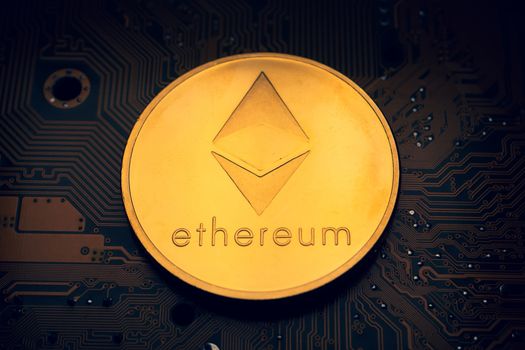 A golden coin with ethereum symbol on a mainboard.