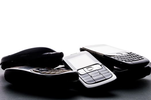 Old and obsoleted cellphones on a black background.