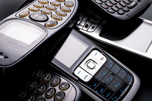 Old and obsoleted cellphones on a black background.