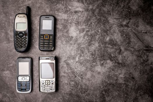 Many obsoleted cellphones on a grunge background.