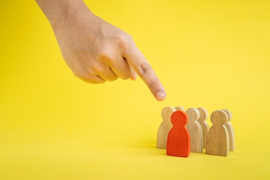 Group of wood figure hand pointing to the team leader in human resource management concepts Teamwork.Success Leadership, Business Progress and Competition on yellow backgrond and copy space