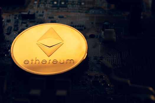 A golden coin with ethereum symbol on a mainboard.